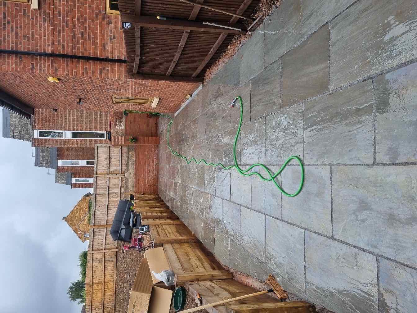 Grey sandstone paving laid along the rear of a house with a garden extension