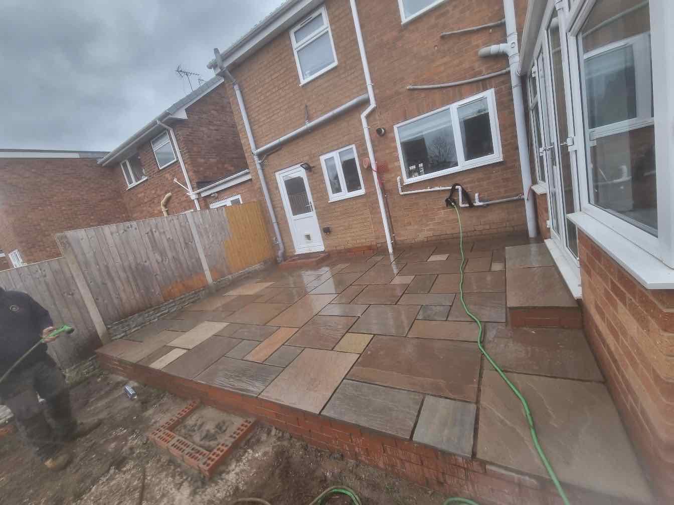 Buff and brown Indian sandstone patio against a semi-detached house